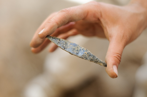 obsidian arrowhead isolated on archaeologic background
