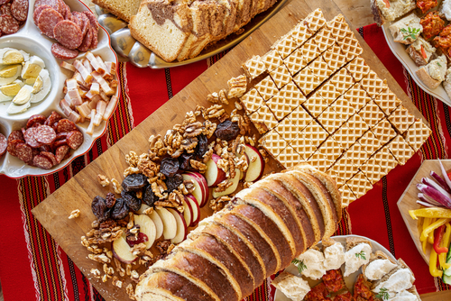 Fresh baked sweet bread and autumn nuts and apples surrounded by traditional food on a table at a local brunch in Romania