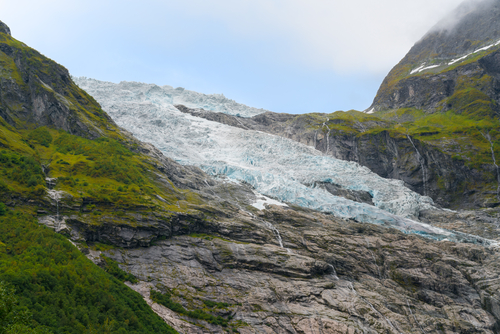 Detail shot of Boyabreen Glacier flowing down the rocky mountain. Norwegian landscape on a day of summer.