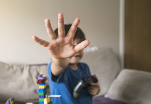 Stop hand sigh from kid, Child boy showing stop gesture with his hand while holding video game console. Concept of domestic violence and child abuseor International human rights or refugee day concept.