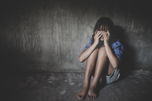 Sad little girl sitting against the wall in despair. 