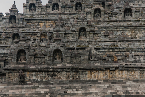 A fragment of the Borobudur Temple exterior with statues of seated Buddha in niches, Yogyakarta, Central Java, Indonesia