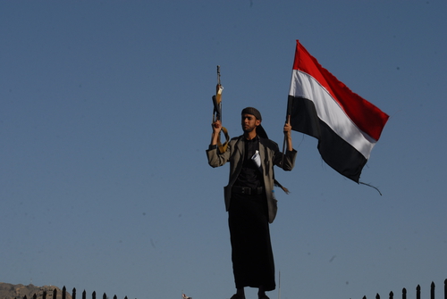 YEMEN, Sanaa : A Shiite-Houthi supporter holds a Yemeni flags and raises his rifle during a demonstration in Sanaa on October 2, 2015, against ongoing military operations carried out by the Saudi-led coalition.