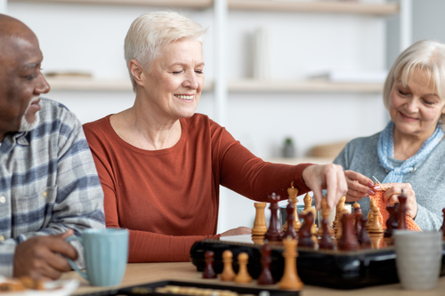 Attarctive senior woman playing chess with multiracial friends