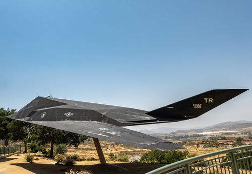 Simi Valley, California, USA - April 27, 2022: Ronald Reagan Presidential Library. Black Authentic F-117A nighthawk first operational stealth aircraft in front of wide hilly landscape.