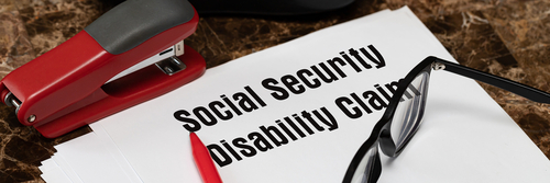 Social Security Disability Claim Concept. An application form on the table next to a red pen and glasses