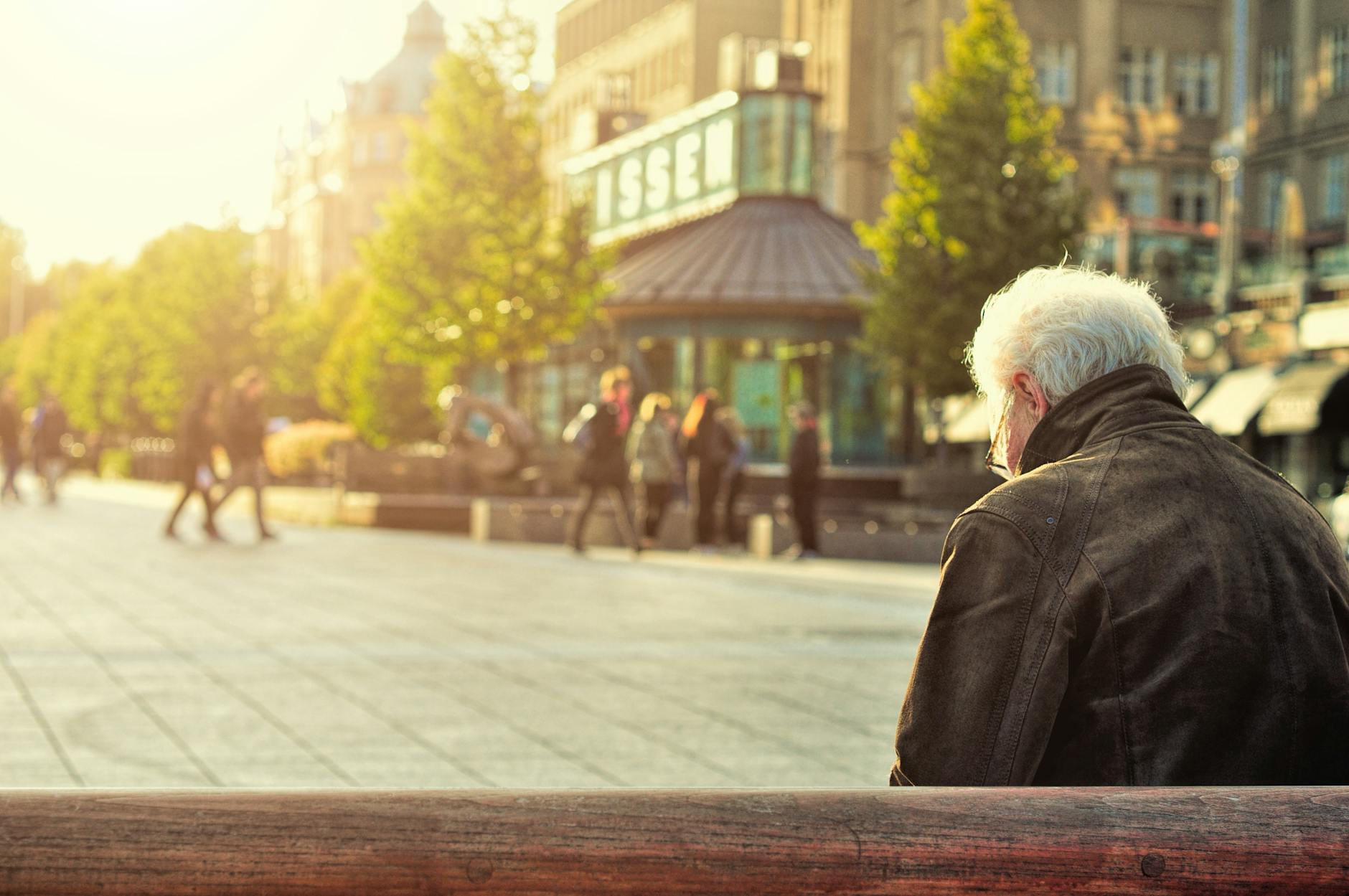 man sitting on wooden bench wearing black leather jacket