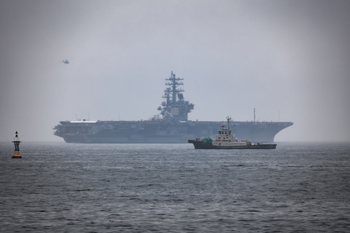 The Japanese tug Uraga sits in Tokyo Bay as the USS Ronald Reagan deploys in the background from her homeport of Yokosuka, Japan.