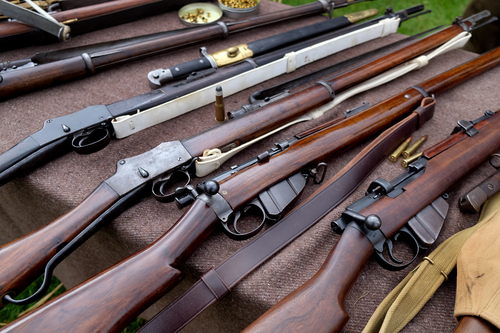 Vintage military rifles and small arms on display at an outdoor event.
