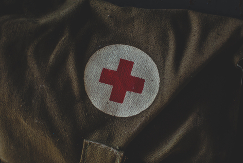 Military and emergency first aid kit in the storage. Medical sign red cross symbol on the green bag