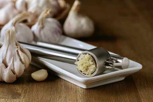Garlic bulbs and garlic press on an old wooden table. 