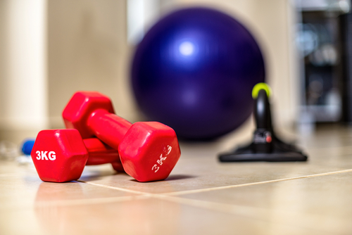 Fitness ball, dumbbells and other sport equipment on the floor of the living room. Home fitness and workout.