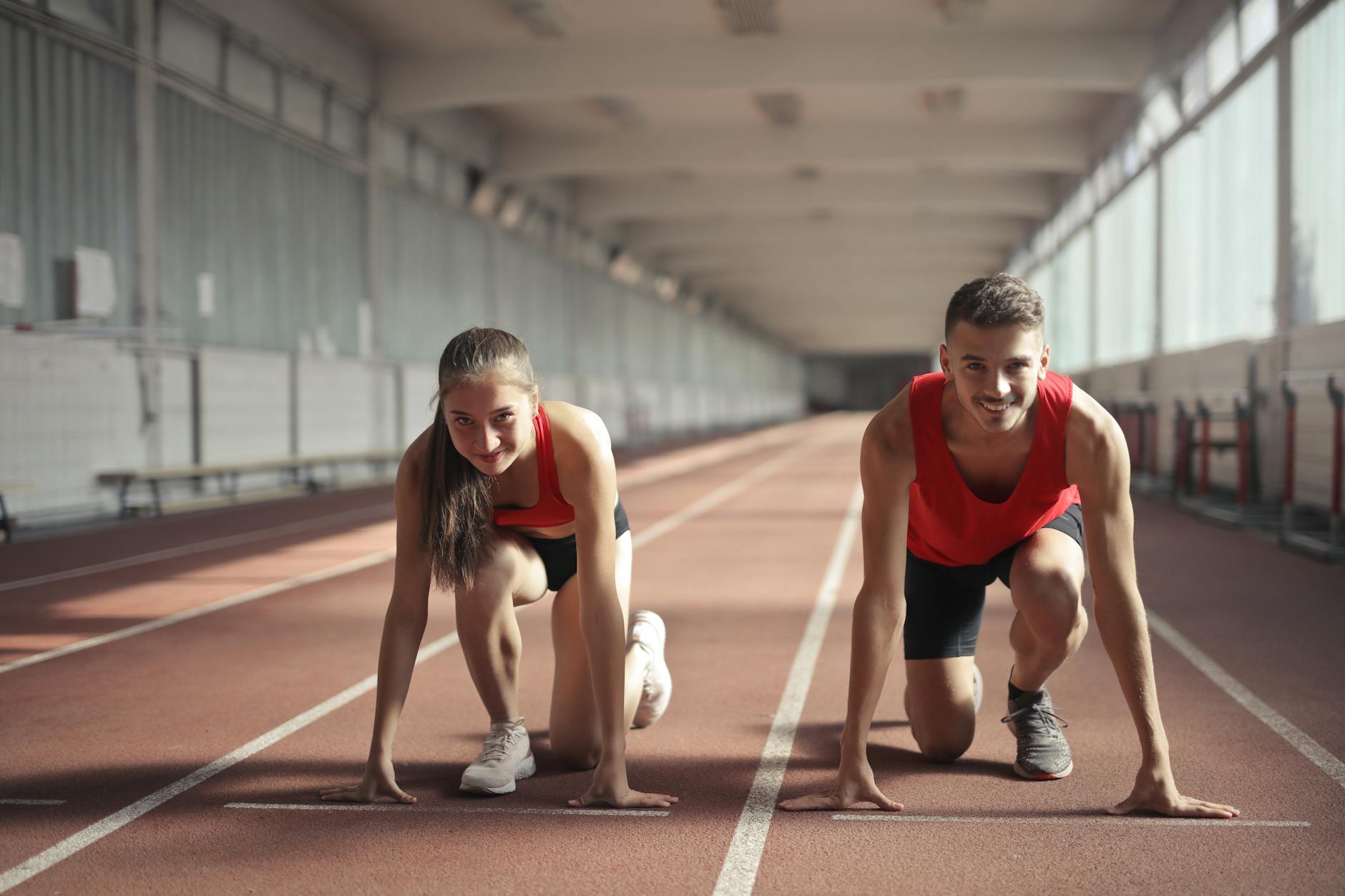 men and woman in red tank top is ready to run on track field